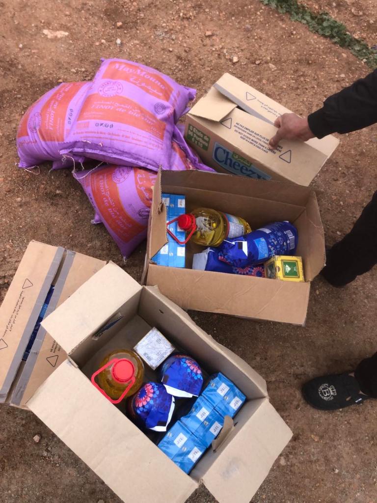 Panier contenant des produits alimentaires essentiels tels que farine, huile, sucre, et thé, préparé pour une distribution solidaire au Domaine Berraha, Sefrou, Maroc.
